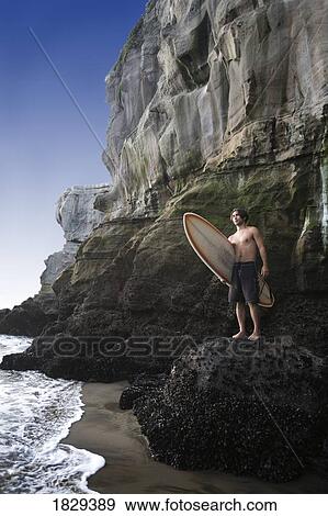 Stock Photo - A surfer on Muriwai Beach, New Zealand. Fotosearch