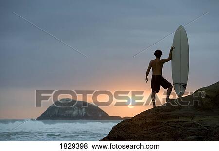 Stock Photo - A surfer on Muriwai Beach, New Zealand. Fotosearch