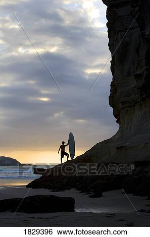 Stock Photograph - A surfer on Muriwai Beach, New Zealand. Fotosearch