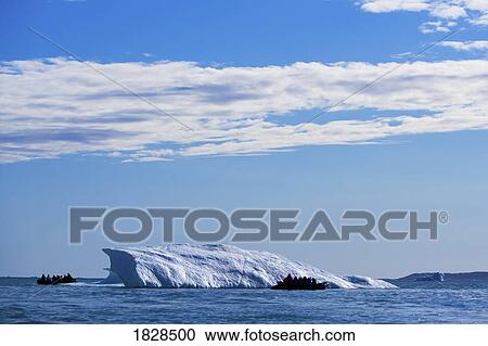 Stock Image - Boats by ice berg off coast of Nunavut, Canada. Fotosearch