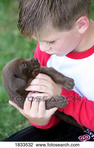 Stock Image - Boy holding puppy. Fotosearch