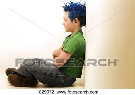 Stock Image - Boy with dyed hair sitting on floor. Fotosearch
