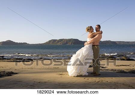 Picture - Bride and groom embracing on beach. Fotosearch