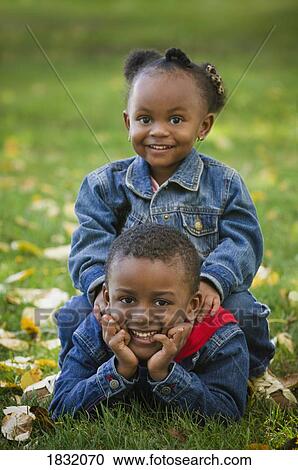 Stock Image - Brother and sister posing in the fall leaves . Fotosearch