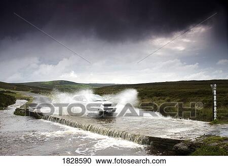 Stock Image - Car driving down flooded road, Yorkshire, England. Fotosearch
