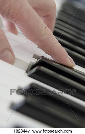 Stock Photo - Close up of finger playing piano keyboard. Fotosearch