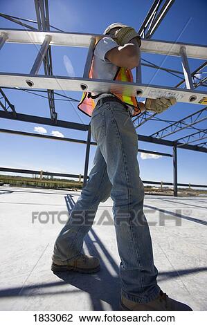 Stock Image - Construction worker carrying a ladder. Fotosearch