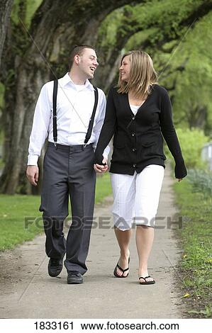Stock Image - Couple holding hands while walking. Fotosearch