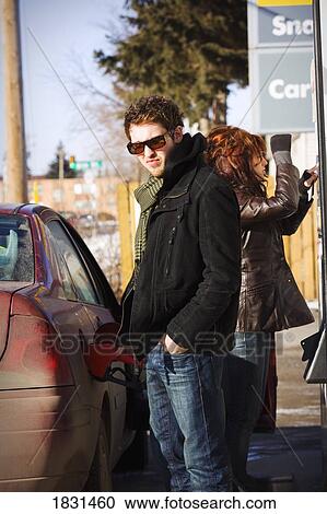 Stock Image - Couple putting gas in car. Fotosearch