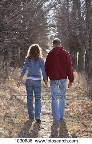 Couple walking while holding hands View Large Photo Image Stock Photograph - Couple walking while holding hands. Fotosearch
