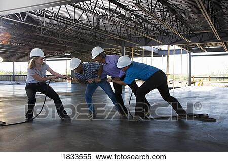 Stock Photography - Engineers playing tug of war on construction site. Fotosearch