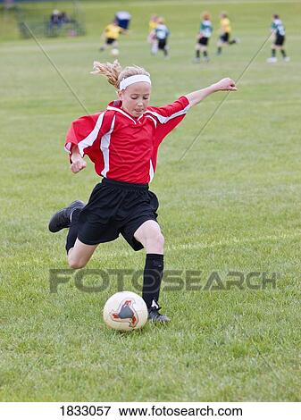Stock Photo - Female soccer player kicking the ball . Fotosearch
