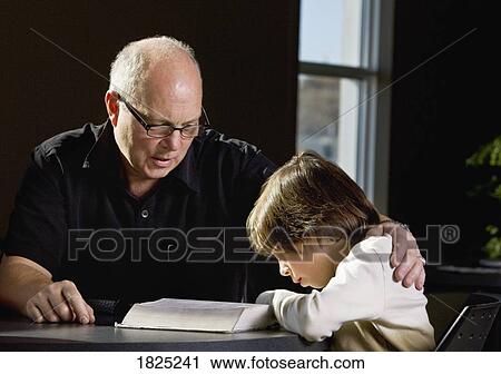 Stock Image - Grandpa helping a child to read. Fotosearch