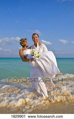 Groom carrying bride on beach View Large Photo Image Stock Image - Groom carrying bride on beach. Fotosearch