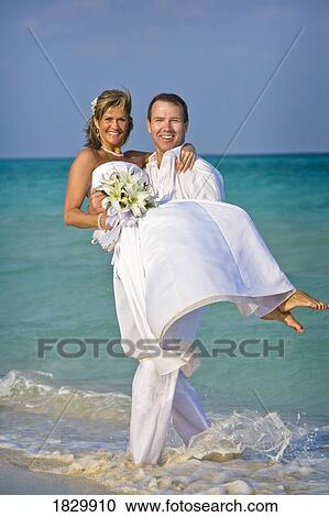 Groom carrying bride on beach View Large Photo Image Stock Image - Groom carrying bride on beach. Fotosearch