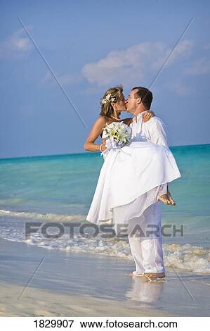 Groom carrying bride on beach View Large Photo Image Stock Photo - Groom carrying bride on beach. Fotosearch