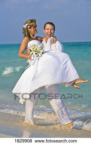 Groom carrying bride on beach View Large Photo Image Stock Photo - Groom carrying bride on beach. Fotosearch