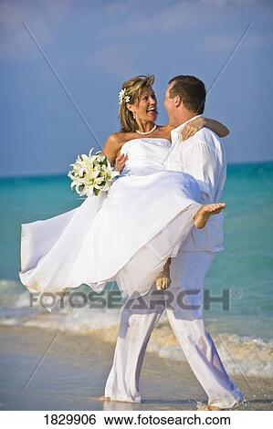 Groom carrying bride on beach View Large Photo Image Stock Photograph - Groom carrying bride on beach. Fotosearch