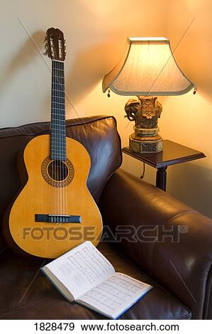 Guitar and book of music on sofa in living room View Large Photo Image Stock Photo - Guitar and book of music on sofa in living room. Fotosearch