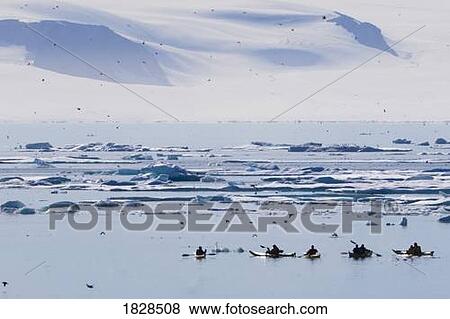 Stock Photo - Kayakers by ice berg off coast of Nunavut, Canada. Fotosearch