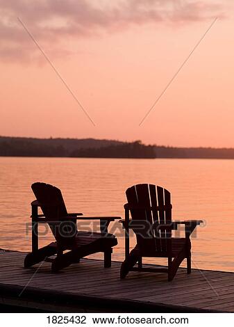 Stock Image - Lake of the Woods, Ontario, Canada, Adirondack chairs on a dock. Fotosearch