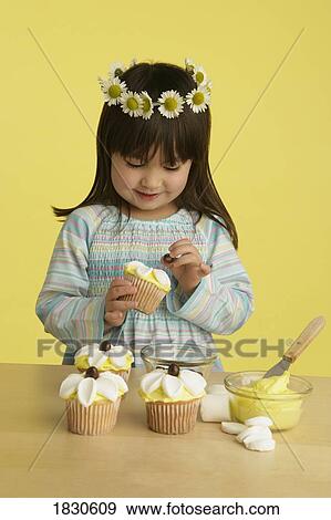 Stock Photo - Little girl decorating cupcakes. Fotosearch