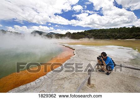 Stock Image - Man at Champagne Pool at geothermal site, Wai-O-Tapu Thermal Wonderland on North Island of New Zealand. Fotosearch