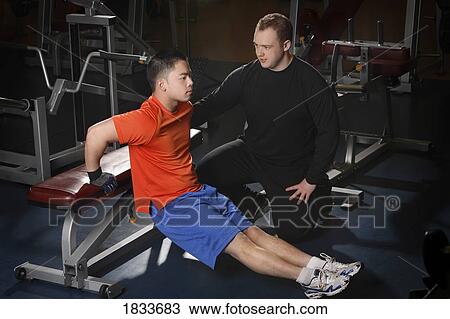 Stock Image - Man exercising with trainer. Fotosearch