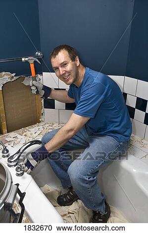 Stock Image - Man fixing bathroom tiles. Fotosearch
