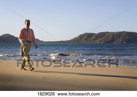 Man in suit walking on beach View Large Photo Image Stock Photograph - Man in suit walking on beach. Fotosearch