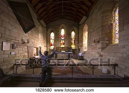 Stock Image - Man praying in chapel, Holy Island, Bewick, England. Fotosearch