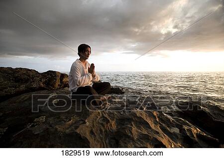 Stock Photo - Man praying on shoreline, Koh Lanta, Thailand, Asia. Fotosearch