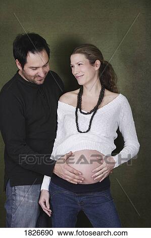 Stock Image - Man with hand on woman's pregnant belly. Fotosearch