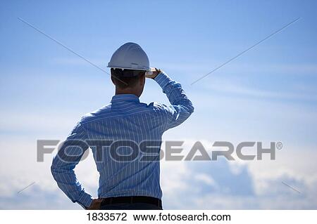Stock Image - Man with hardhat looking into the sky. Fotosearch