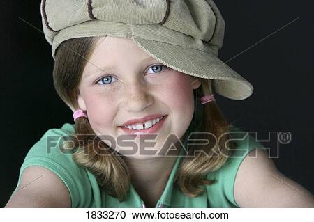 Stock Image - Portrait of young girl with pigtails and hat. Fotosearch