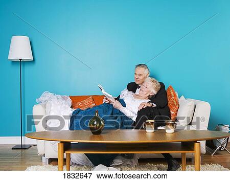 Stock Photo - Senior couple reading on the couch together. Fotosearch
