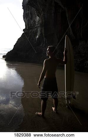 Stock Photo - Surfer at Muriwai, New Zealand. Fotosearch