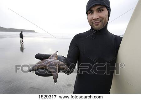 Stock Photo - Surfer holding starfish. Fotosearch