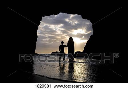 Surfer inside a cave at Muriwai, New Zealand View Large Photo Image Stock Image - Surfer inside a cave at Muriwai, New Zealand. Fotosearch