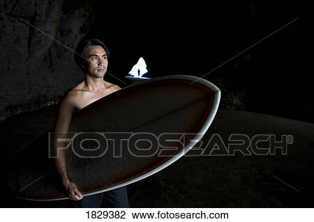 Surfer inside a cave at Muriwai, New Zealand View Large Photo Image Stock Image - Surfer inside a cave at Muriwai, New Zealand. Fotosearch