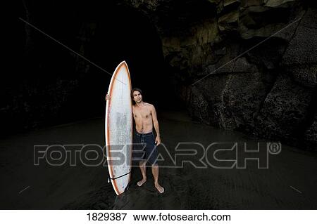 Surfer inside a cave at Muriwai, New Zealand View Large Photo Image Stock Photo - Surfer inside a cave at Muriwai, New Zealand. Fotosearch