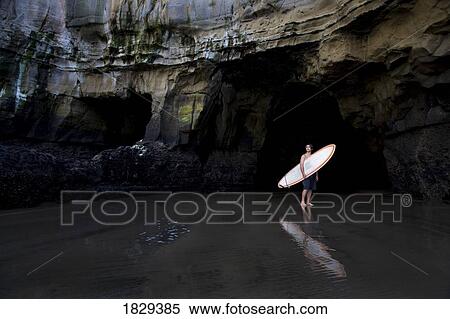 Stock Photography - Surfer inside a cave at Muriwai, New Zealand. Fotosearch