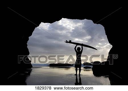 Stock Photo - Surfer inside a cave at Muriwai, North Island, New Zealand. Fotosearch