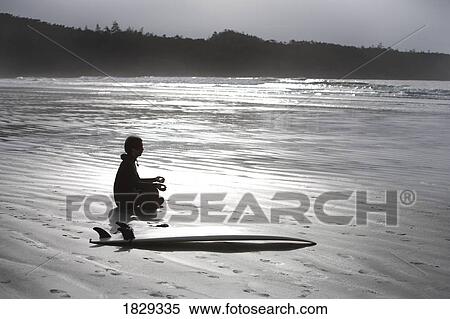 Stock Photography - Surfer meditating on beach, Cox Bay near Tofino, British Columbia, Canada. Fotosearch