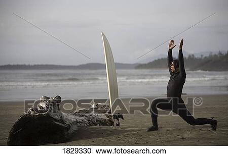 Stock Image - Surfer stretching on beach, Cox Bay near Tofino, British Columbia, Canada. Fotosearch