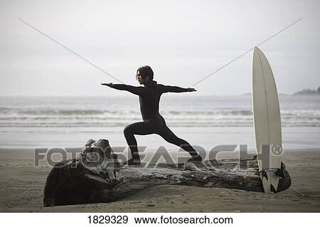 Stock Photo - Surfer stretching on beach, Cox Bay near Tofino, British Columbia, Canada. Fotosearch
