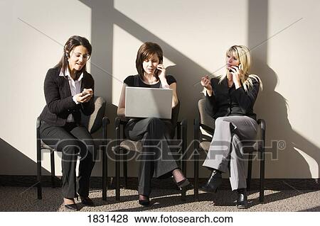 Stock Photo - Three women sitting, talking on cell phones. Fotosearch