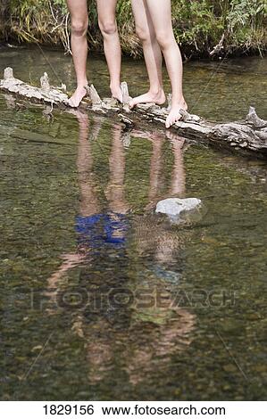 Two girls standing on log in stream View Large Photo Image Stock Photograph - Two girls standing on log in stream. Fotosearch