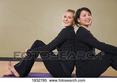 Stock Photography - Two women sitting back to back. Fotosearch