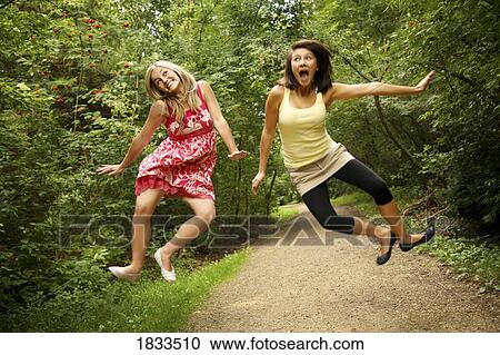 Two young women jumping excitedly into the air View Large Photo Image Stock Image - Two young women jumping excitedly into the air. Fotosearch